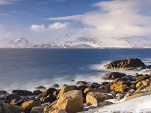 Rocky coast, snow-capped mountains in the background