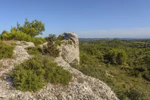 A rocky hill with a view of a town in the distance