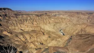 Rocky landscape with deeply cut river in an extensive desert region in bright sunshine
