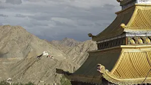 Roof of a Tibetan Buddhist temple with mountain backdrop and dramatic sky