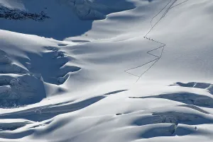 Roped party climbing down the glaciated mountainside of the Mt Piz Palue