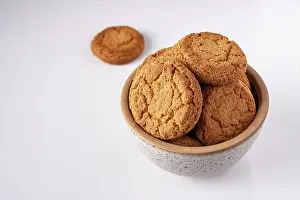 Round oatmeal cookies lie in a gray ceramic bowl