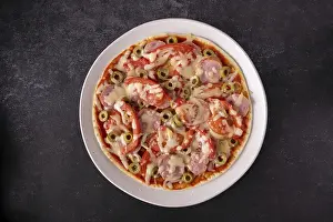 Round pizza on a plate, on a black background