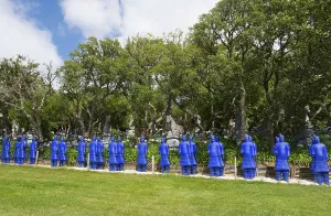 A row of blue terracotta soldier statues stands in a park-like setting