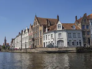 Row of historic buildings along a canal with detailed architecture and clear sky