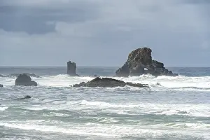 A rugged coastal landscape with rocks in the sea and a cloudy sky