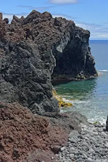 Rugged coastline with steep volcanic cliffs jutting out into the deep blue sea