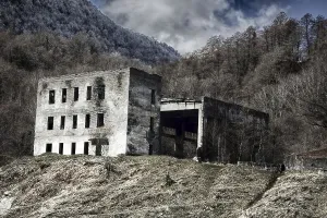 The ruins of a three-storey house with a hangar on the background of winter forest mountains