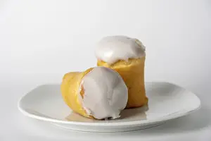 Two rum buns with icing on white plate, copy space
