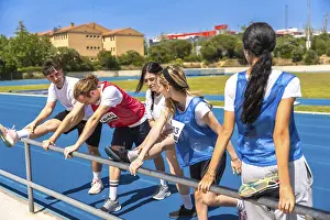 Runners stretching their legs on a vibrant blue track