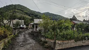 A rural village with green hills and a quiet village road