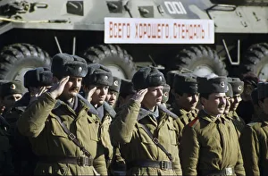 Russian soldiers saluting in front of a train transporting armoured vehicles during the withdrawal of Soviet troops