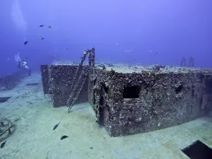Rusty shipwreck with corals and fish in deep water