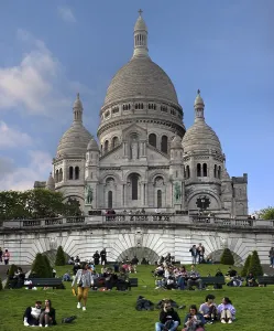 Sacre Coeur de Montmartre, in front tourists in a meadow