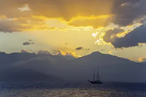 A sailboat on the sea in front of a dramatic sunset