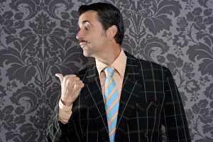 Salesperson portrait pointing with thumb finger on wallpaper background