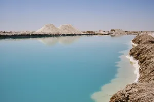 Salt lake with turquoise water and white salt hills on the shore