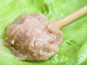 Salty caviar of zander fish in wooden spoon on green leaf close up