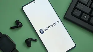 Samsara logo displayed on a smartphone with earbuds and keyboard nearby
