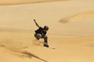 Sand boarding in the dunes of the Namib Desert