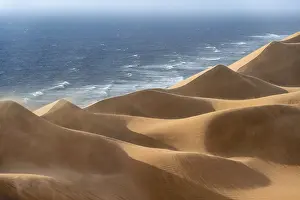 Sand dunes with wave patterns and sea in evening light
