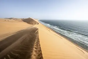 Sand dunes with wave patterns and sea in evening light