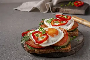Sandwiches with egg and vegetables on a wooden board on a gray background