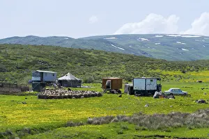 Scene with farm and flock of sheep on green fields surrounded by mountains