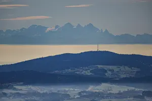 This scene shows the majestic Dachstein Mountains in the Eastern Alps in the distance as soft clouds of fog surround