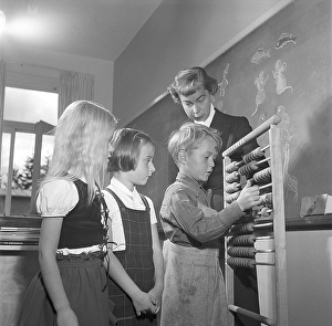 School in the 1950s. The female schoolteacher watches as her first grade pupils are learning how to count