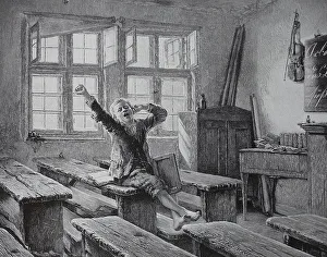 A schoolboy has to sit alone after school in the classroom and stretches out from fatigue