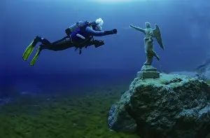 Scuba diver in a mountain lake with a statue of an angel