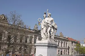 Sculptures in front of a historic building under a blue sky