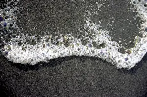 Sea foam on black lava sand