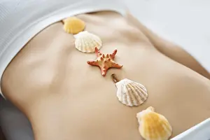 Sea shells and sea star on woman abdomen
