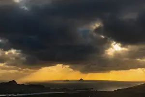 Seashore with the mountain peaks of the Skelligs in the background and dramatic cloudy sky