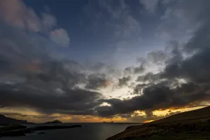 Seashore with the mountain peaks of the Skelligs in the background and dramatic cloudy sky