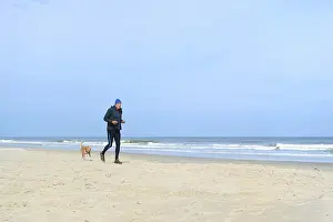 Senior man with dog running together at the beach