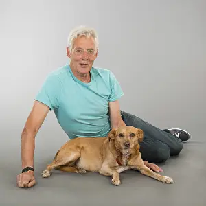 Senior man with his dog in studio on gray background