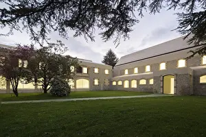 A serene evening scene showcases a historic stone hospital with glowing windows