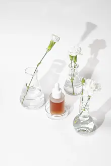 A serene setting of laboratory glassware featuring a skincare serum and fresh flowers