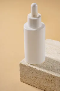 Serum in glass bottle with dropper lid on natural sandstone