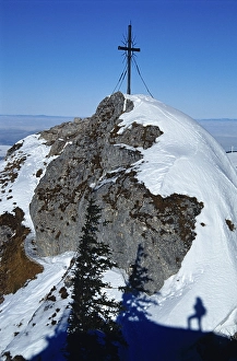 Shadow of a man in the snow under the summit cross of the Steinerner Jaeger Mountain