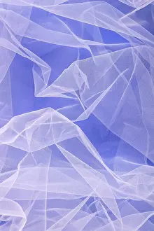 Sheer tulle fabric arranged in soft folds on a blue background