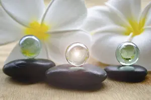 A shining marble on top of black zen stones with beautiful white flower background