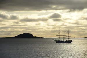 Category Scandinavia Prints: Ship sailing past an island at sunset