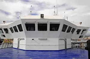 Ship's wheelhouse on blue ground under a changeable sky