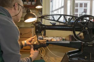 Shoemaker, shoemaker sews shoe to machine