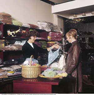 Shopping in the 1960s. Interior of a fashion shop where a woman is showing a female customer a swimming costume
