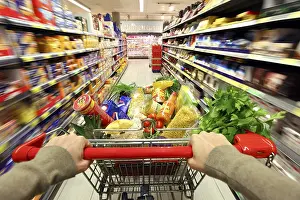 Full shopping trolley being pushed down the aisle